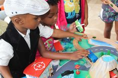 two young children playing with toy trains and cars in a play area at a birthday party