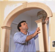 a man holding a fan in his hand and looking up at the ceiling through an archway