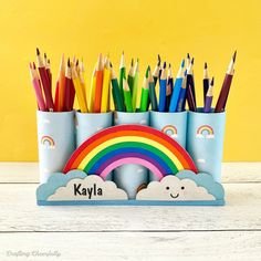 several pencils in cups with rainbow and clouds