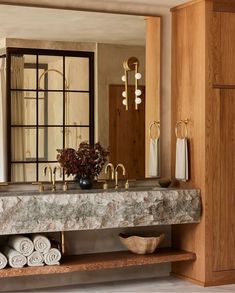 a bathroom with marble counter tops and gold fixtures, along with towels on the shelf