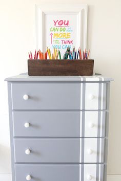 a dresser with some colorful pencils in it and a picture frame on the top