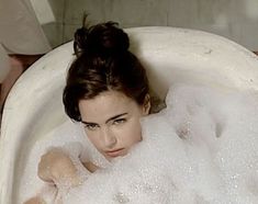 a woman sitting in a bathtub with bubbles on it