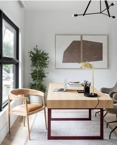 an office with two chairs and a desk in front of a window, next to a potted plant