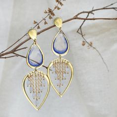 These Water Dew Drops Transparent Blue Resin Earrings are a delicate and elegant accessory, perfect for adding a touch of serenity to any look. The design features teardrop-shaped transparent blue resin pieces that evoke the purity of water droplets. Below, the open heart-shaped frame adorned with tiny golden chains and beads enhances the illusion of glistening dew. These earrings beautifully capture the essence of a fresh morning dew and are sure to charm those who appreciate nature-inspired jewelry.  The earrings dangle gracefully from gold-plated hooks, ensuring they are lightweight and comfortable for all-day wear. Whether you're dressing up for a special occasion or adding a unique flair to your everyday outfit, these resin earrings are sure to draw compliments and spark conversations Blue Pierced Drop Chandelier Earrings, Handmade Blue Drop Earrings, Blue Teardrop Metal Chandelier Earrings, Blue Metal Teardrop Chandelier Earrings, Blue Dangle Teardrop Earrings, Blue Drop Earrings Pierced, Blue Teardrop Chandelier Earrings For Pierced Ears, Blue Danglers For Gift, Light Blue Drop Earrings With Dangling Beads