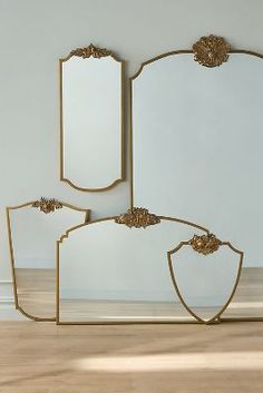 three mirrors sitting next to each other on top of a wooden floor in front of a white wall