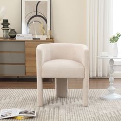 a white chair sitting on top of a rug in a living room next to a window