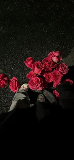 a person's feet with red roses on the ground