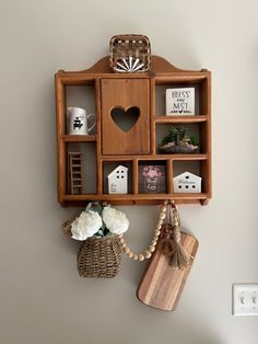 a wooden shelf with various items on it and a basket hanging from the wall next to it