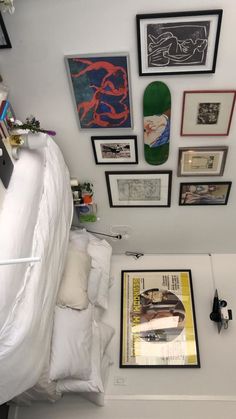 there is a bed with white sheets and pictures on the wall next to it,