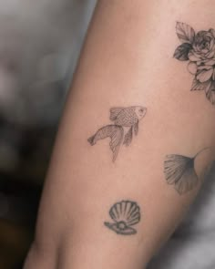 a woman's arm with fish and flowers on it