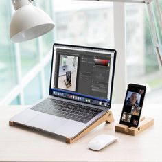 an open laptop computer sitting on top of a wooden desk next to a cell phone