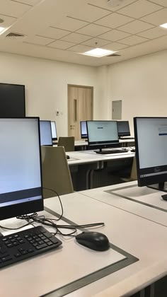 three computer monitors sitting on top of a white desk next to a keyboard and mouse