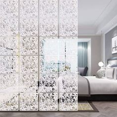 a bedroom with a bed and white walls in the background is an open door to a room that has a large mirror on it