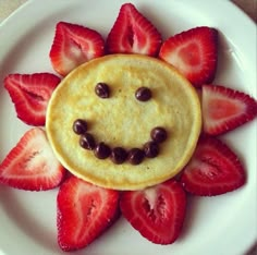 a smiley face made out of strawberries on a white plate with chocolate chips in the shape of a sunflower