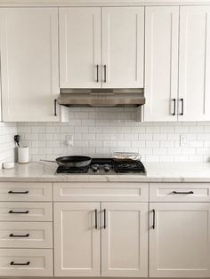 a kitchen with white cabinets and black stove top