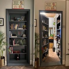 an open book case in the corner of a room with plants and books on it