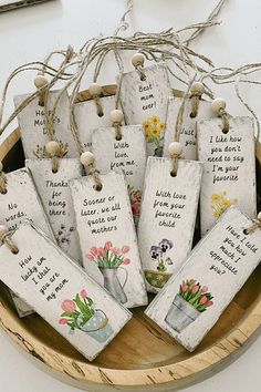 wooden tags with flowers and sayings on them in a wood bowl hanging from twine