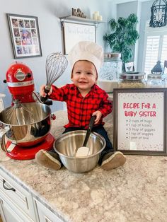 a baby in a chef's hat sitting on top of a counter next to a mixing bowl