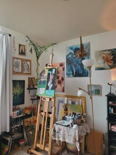 an artist's studio with easel, canvass and paintings on the wall