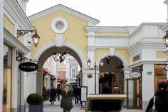 people are walking down the street in front of shops