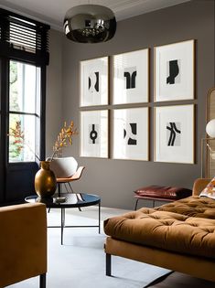 a living room filled with furniture and pictures on the wall next to a window in front of a couch