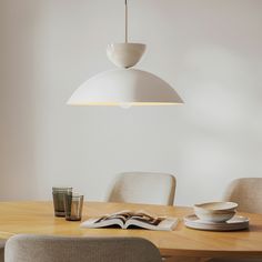 a dining room table with a book on it and a light fixture hanging over it