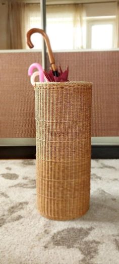 an umbrella is placed in a basket on the floor