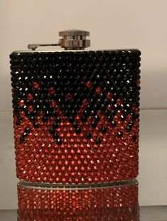 a red and black flask covered in lots of beads