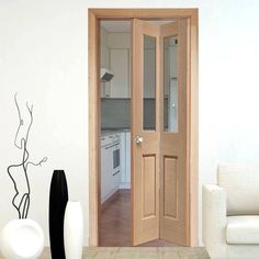 an open door leading to a kitchen and living room with white furniture in the background