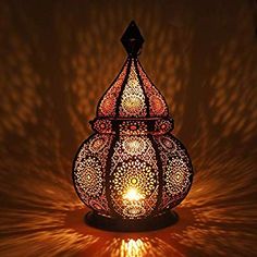 an intricately designed lamp is lit up in the dark with light coming from it