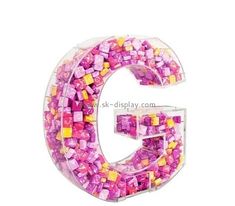 the letter c is made out of pink and yellow cubed beads on a white background