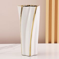 a white and gold vase sitting on top of a table