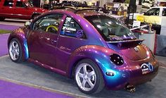 a purple car parked in a showroom next to other cars