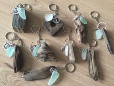 several different types of sea glass and driftwood keychains on a wooden table