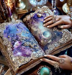 a woman is holding an open book in her hands with jewelry on the table next to it