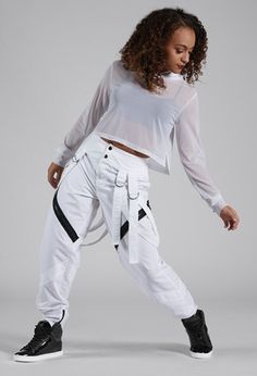 a woman in white is posing with her hands on her hips and wearing black sneakers