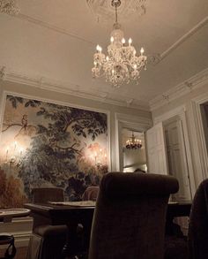 a chandelier hangs from the ceiling above a dining room table with two chairs