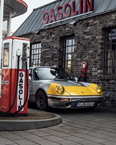 a yellow and silver car is parked in front of a gas station with an old brick building