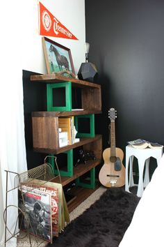 a room with a guitar, bookshelf and other items