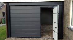 an open garage door on the side of a house with grass in front of it