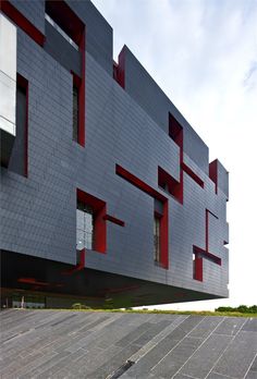 the building has red and white windows on it's front side, as well as an open parking lot