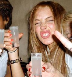 three people holding up glasses with drinks in front of their faces and making silly faces