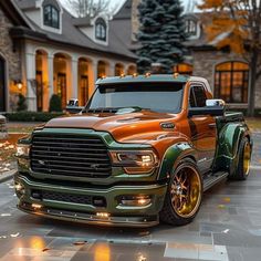 an orange and green truck is parked in front of a large house with its lights on