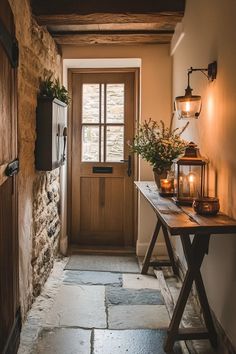 an entry way with candles and flowers on the table next to the front door is lit by two lanterns