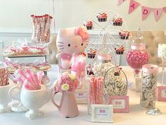 a table topped with lots of candy and candies next to a hello kitty cupcake