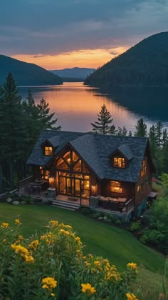 a large house sitting on top of a lush green hillside next to a body of water