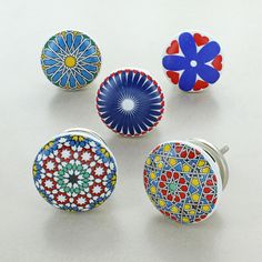 four different colored knobs with designs on them sitting next to each other in front of a white background