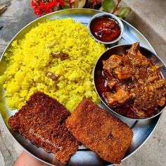 a plate with rice, meat and sauces on it next to some red flowers