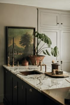 a kitchen with marble counter tops and gold faucets on the sink, next to a painting