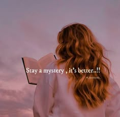 a woman with long red hair is looking at the sky while holding an open book